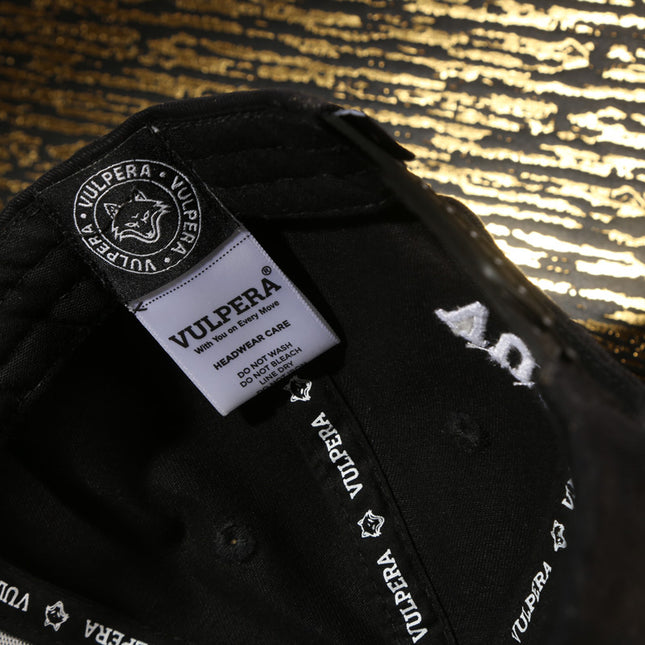 Black cap with Vulpera branding on the inside label