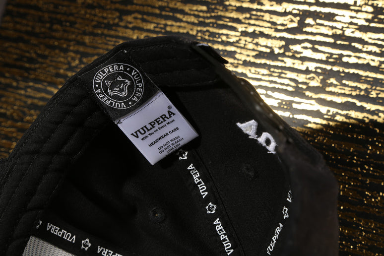 Black cap with Vulpera branding on the inside label